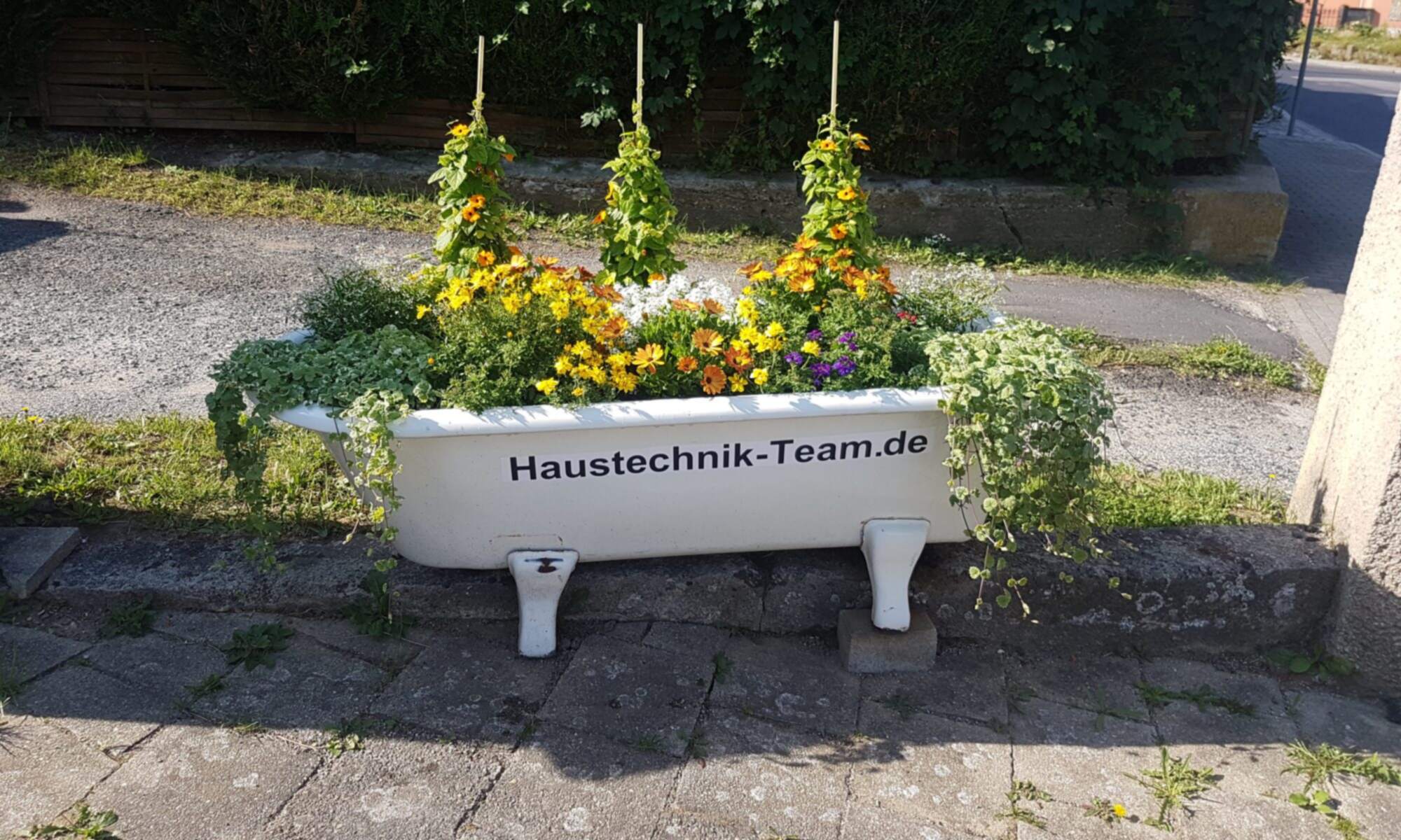 Bild einer Badewanne mit der Aufschrift Haustechnik-Team.de und Blumen darin vor unserem Büro